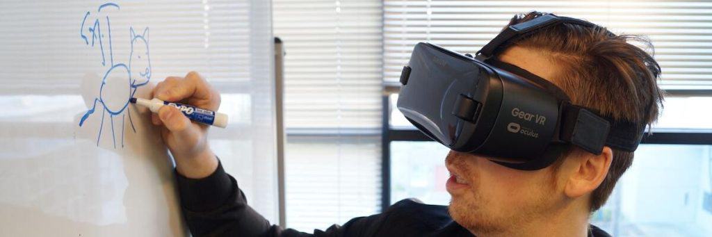 A gamer wearing VR goggles draws what he sees on his augmented reality games to whiteboard.