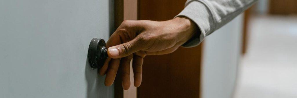 A man's hand ringing a doorbell.