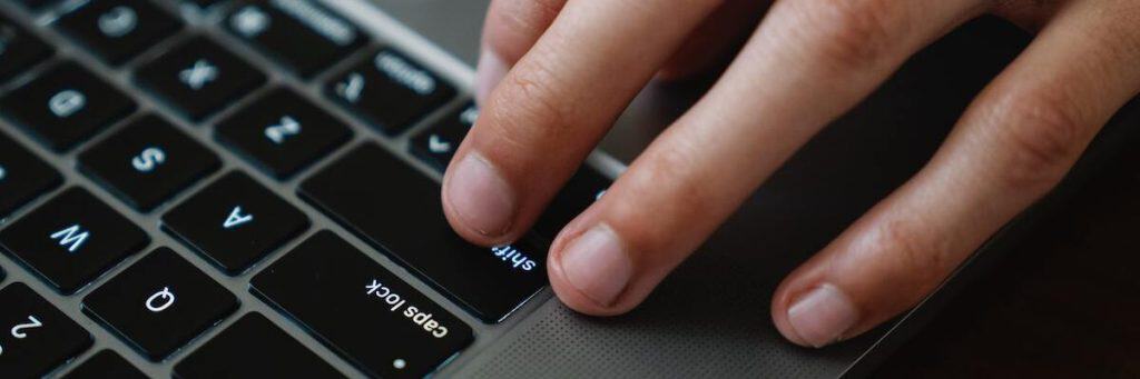 A typist's fingers on a keyboard for writing essays using ChatGPT.
