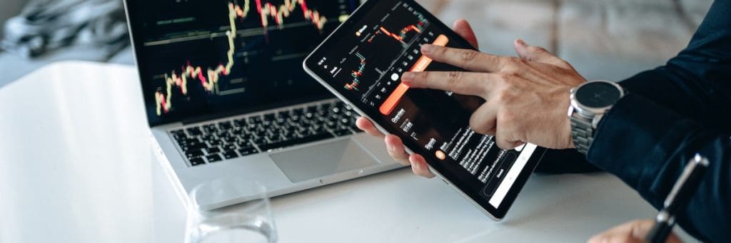 A user is holding statistics of emerging technologies on a tablet next to a writing pad and a keyboard.