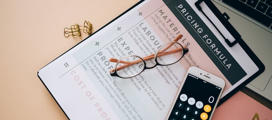 Business plan inputs printout on a clip board that has goggles and a calculator on it.